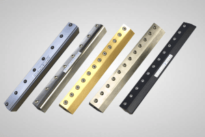 An image of five Air Knives side by side, from left to right, a aluminium and silver air knife, then a black and silver air knife , then a golden coloured air knife and a brass coloured Air Knife then a black air knife